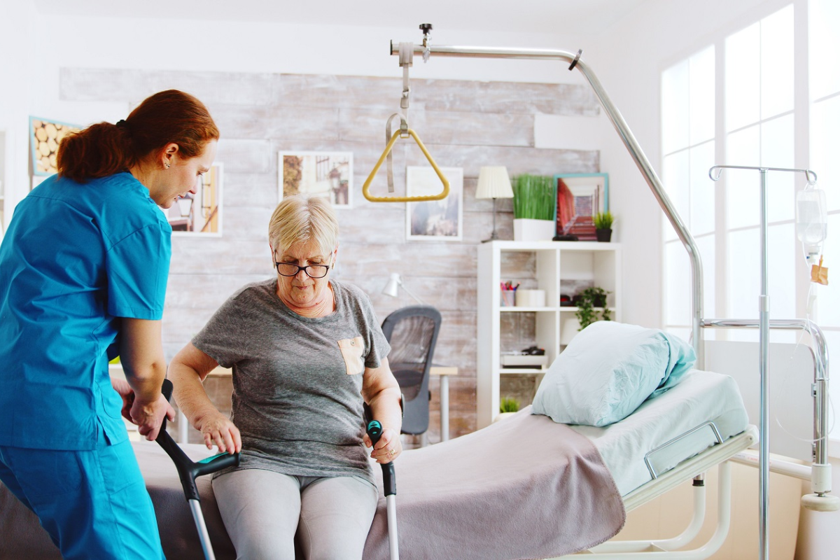 Barrière de sécurité et potence de lit installées sur un lit médicalisé à domicile